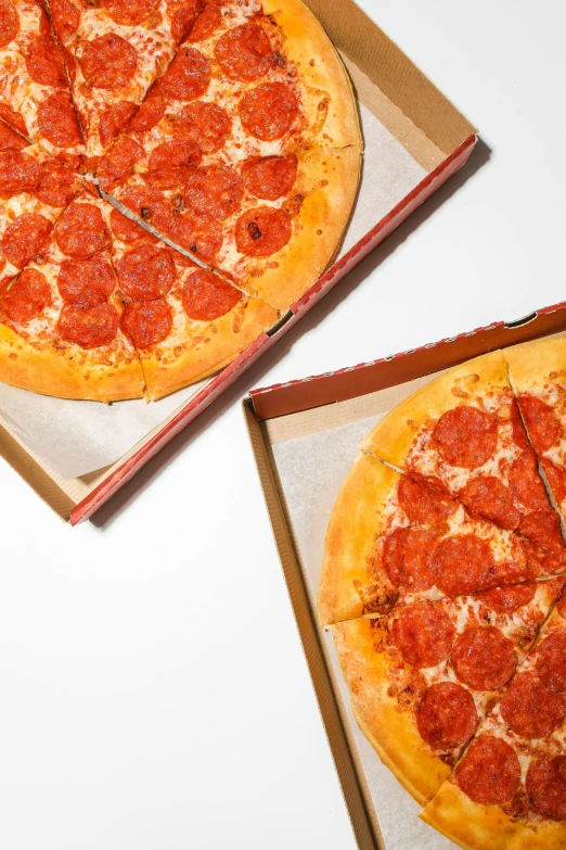 two pizzas sitting in pizza boxes on top of a counter