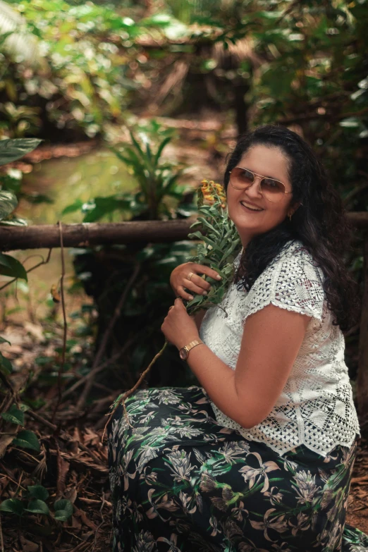 a woman sitting on the ground holding a flower