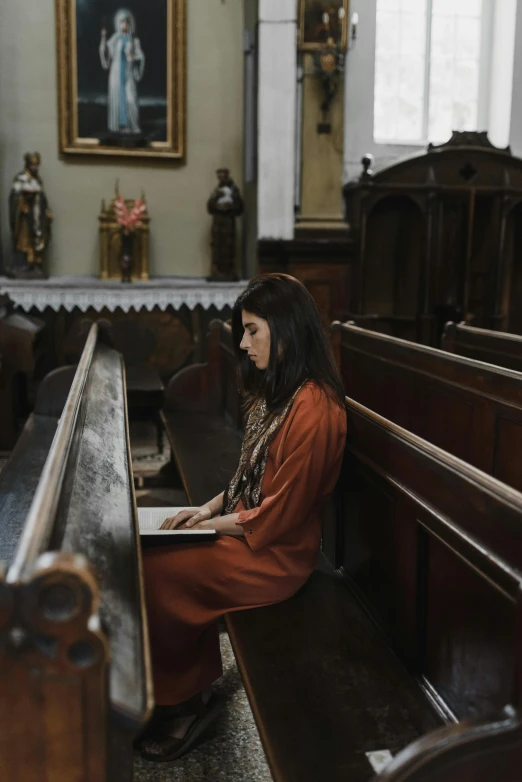 a woman in a red coat is sitting at a pew