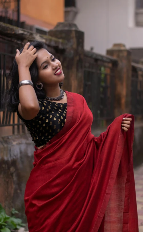 a woman in a red and black saree posing for a picture
