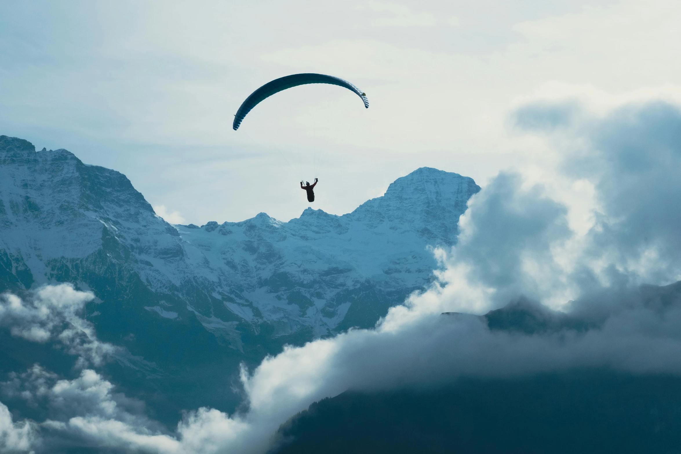 a parachute is suspended above the mountains with some clouds