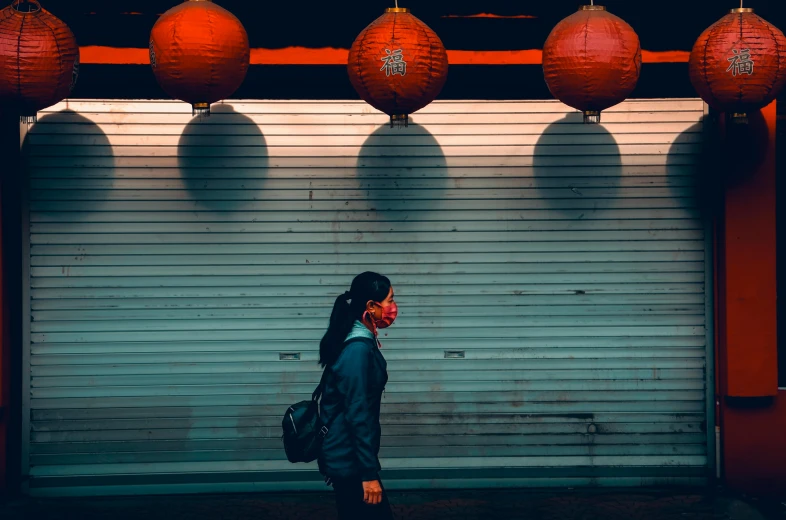 a woman with a black coat, red chinese lanterns and a hand bag on her head