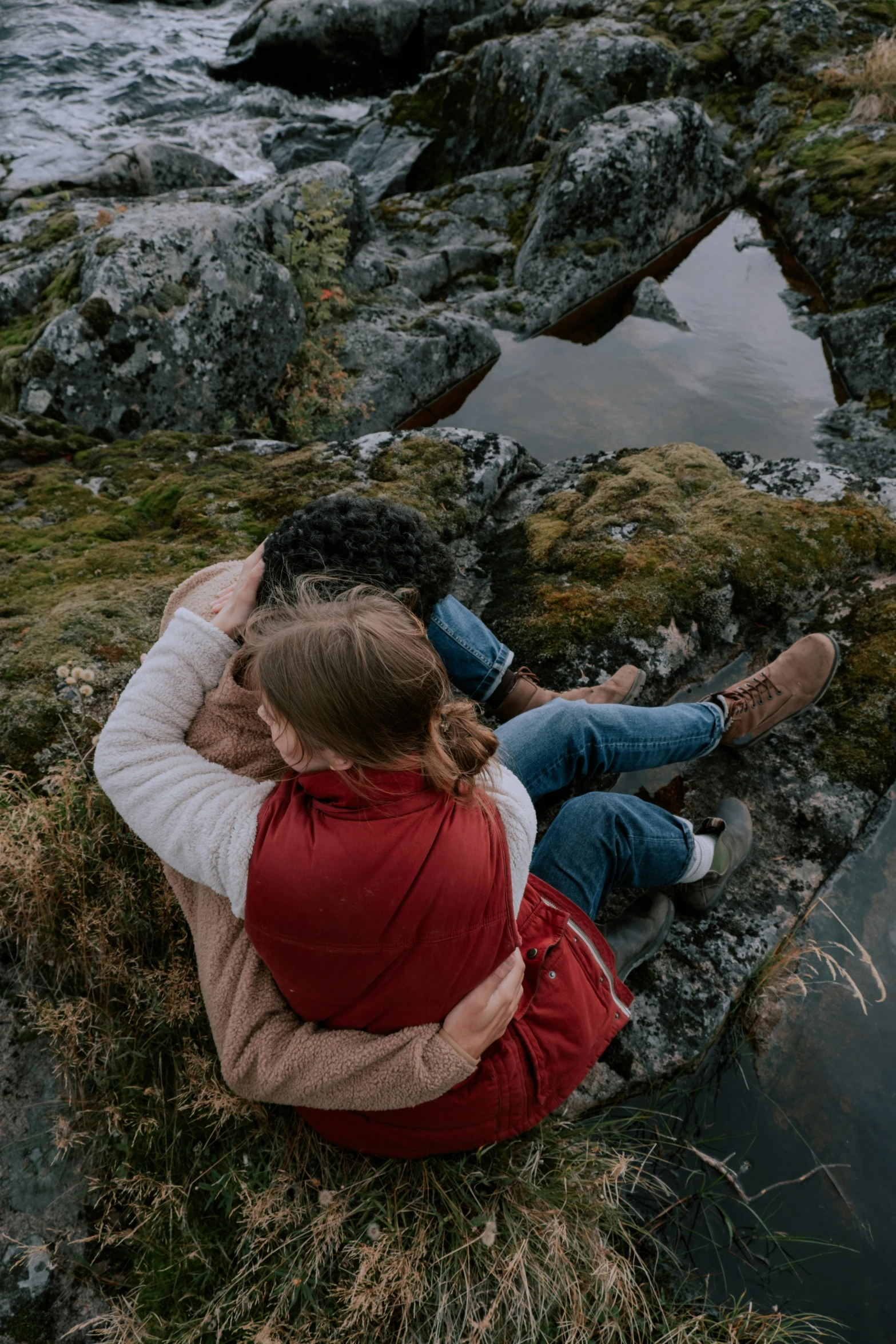 a man and a woman sit by a river together