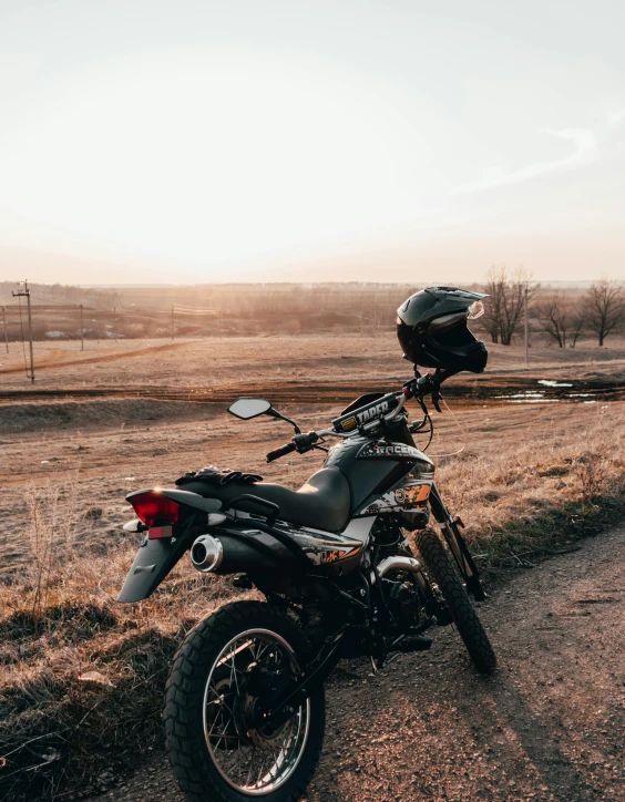 motorcycle parked on a dirt road beside a country road