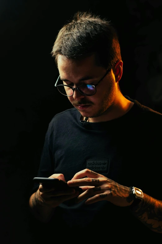 a man wearing glasses looking down at his cell phone