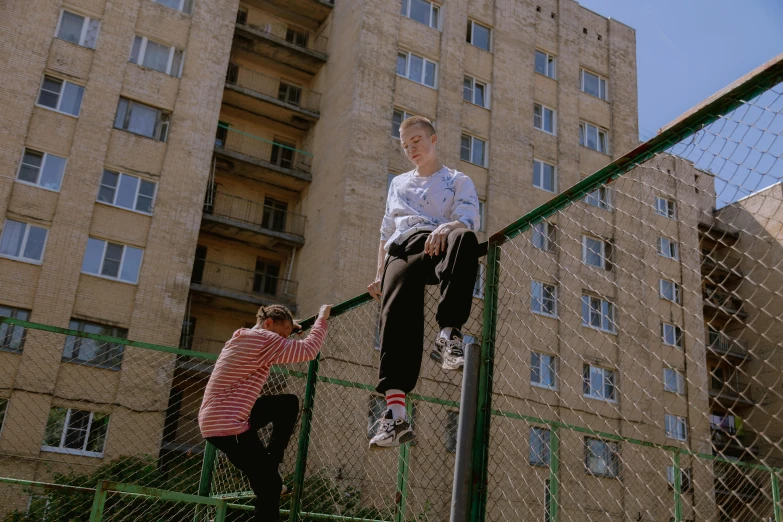 two children climbing on a rail outside in the city