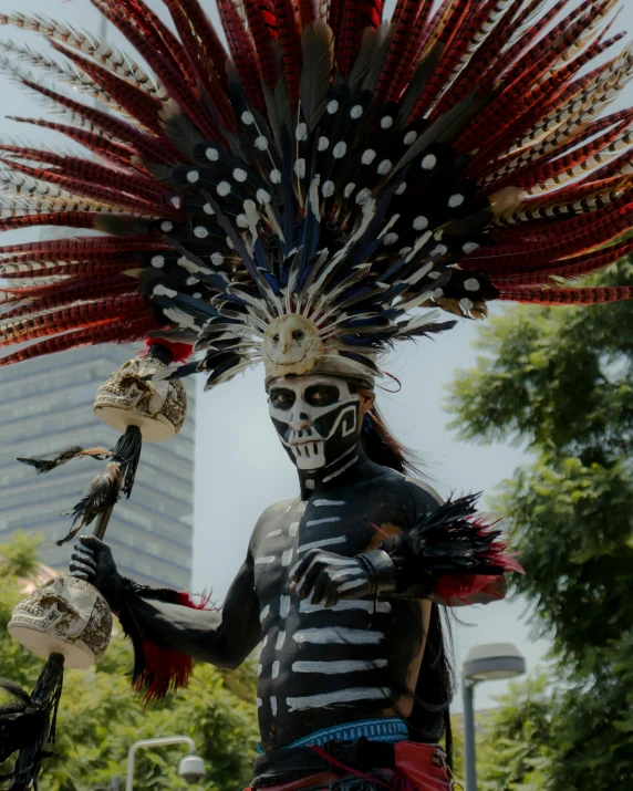 the skeleton man with his headdress is playing the drum