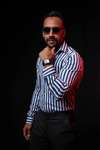 man in blue and red striped shirt wearing sunglasses and looking pensive