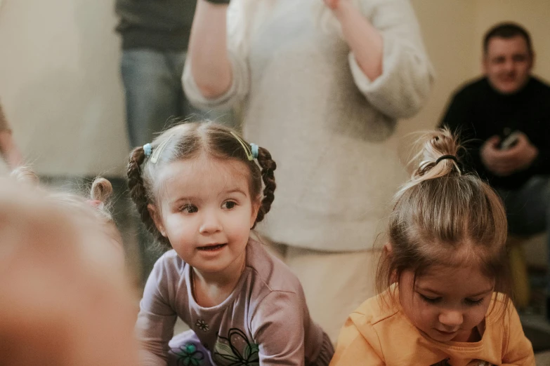 two little girls sitting on the ground and playing with a piece of cake