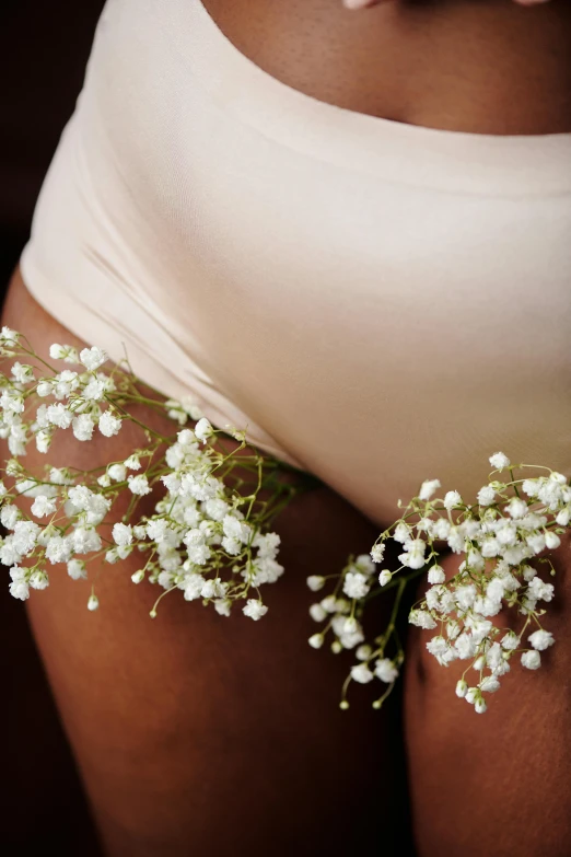 a pregnant woman is holding the belly with small flowers