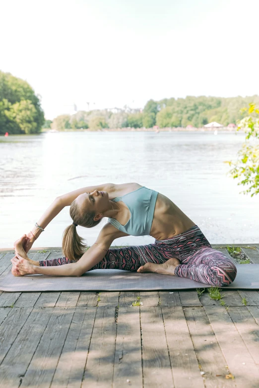 a woman in a yoga pose on a dock next to the water