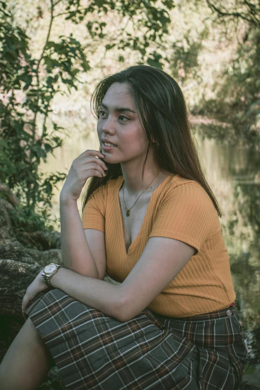 a woman sitting on a tree log by the water