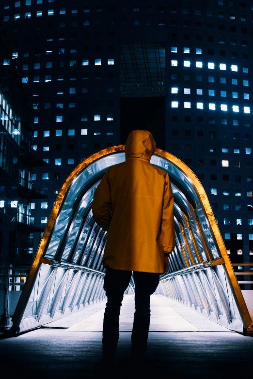 man in yellow coat standing under bridge on pavement