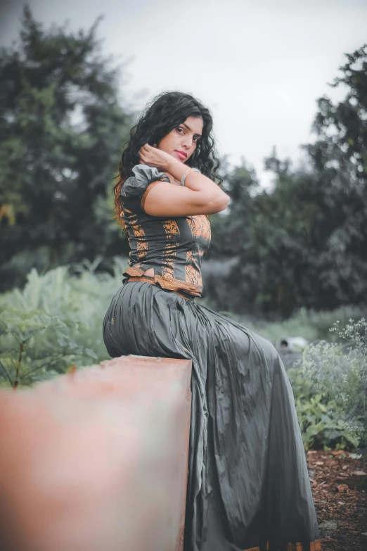 a lady sitting on a stone wall in a dress