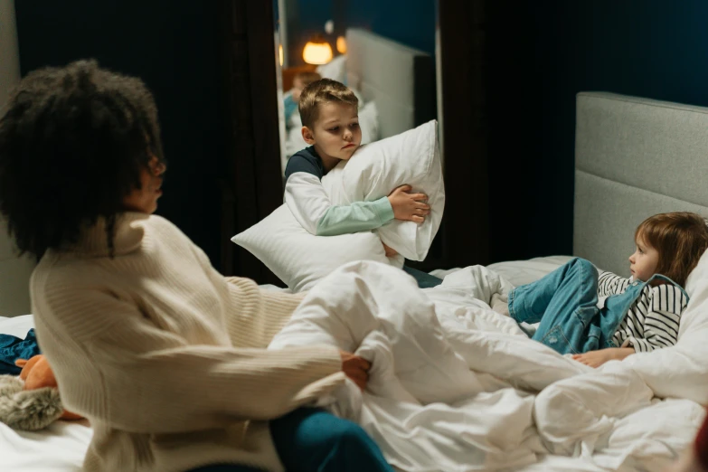 two women sit on a bed as a child lays down