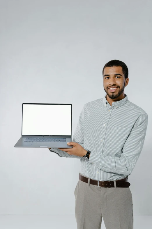 a man is holding a laptop computer with a white screen