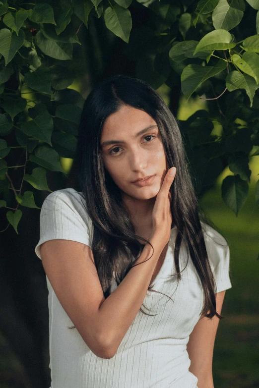 young woman with long hair posing under tree