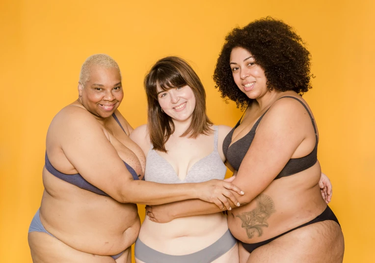 three women standing in front of a yellow background