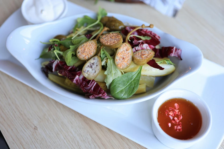 a white bowl filled with salad next to dipping sauce