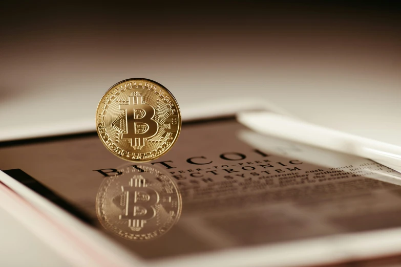 a bitcoin sits atop a magazine next to some white paper