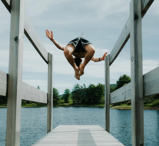 a person jumping into the air off a pier over water