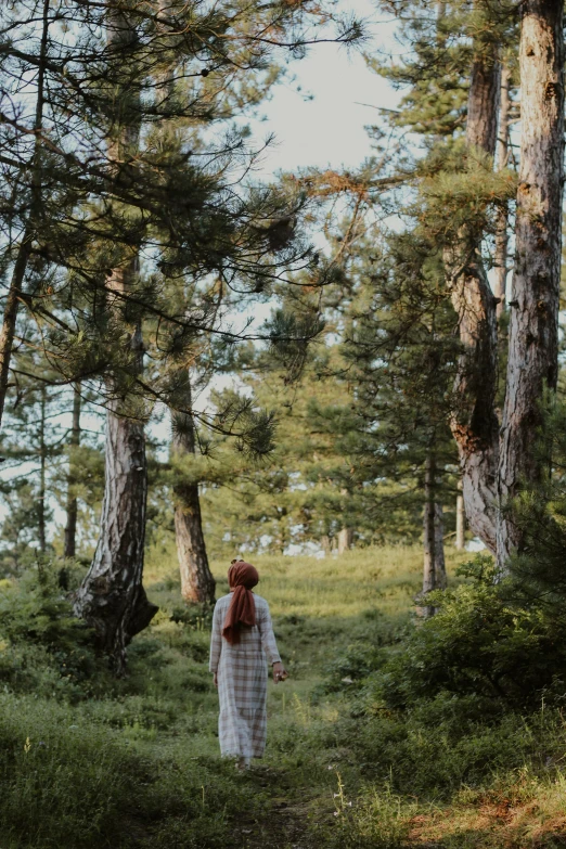 woman in dress walking through a forest with trees