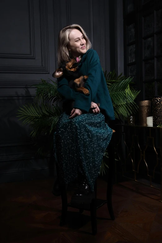 a woman sitting on a chair with a small dog in her lap