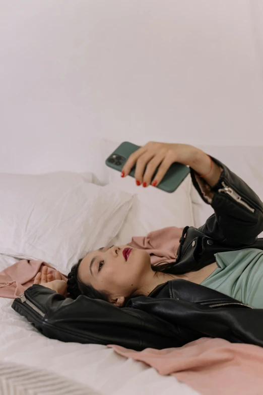 a woman lying on top of a bed with her phone