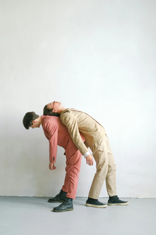 two men leaning against the wall while wearing suits