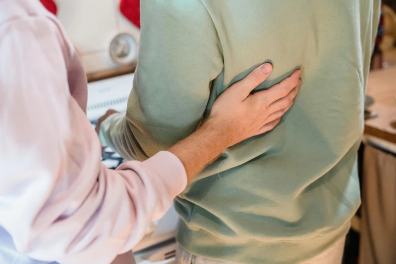 a man wearing a green sweater is hugging a woman