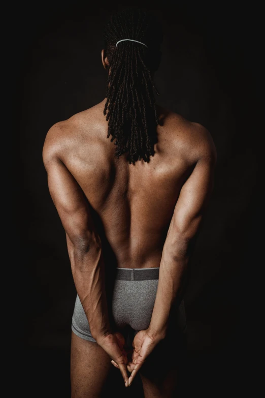 a man with a beard in underwear looking at his back