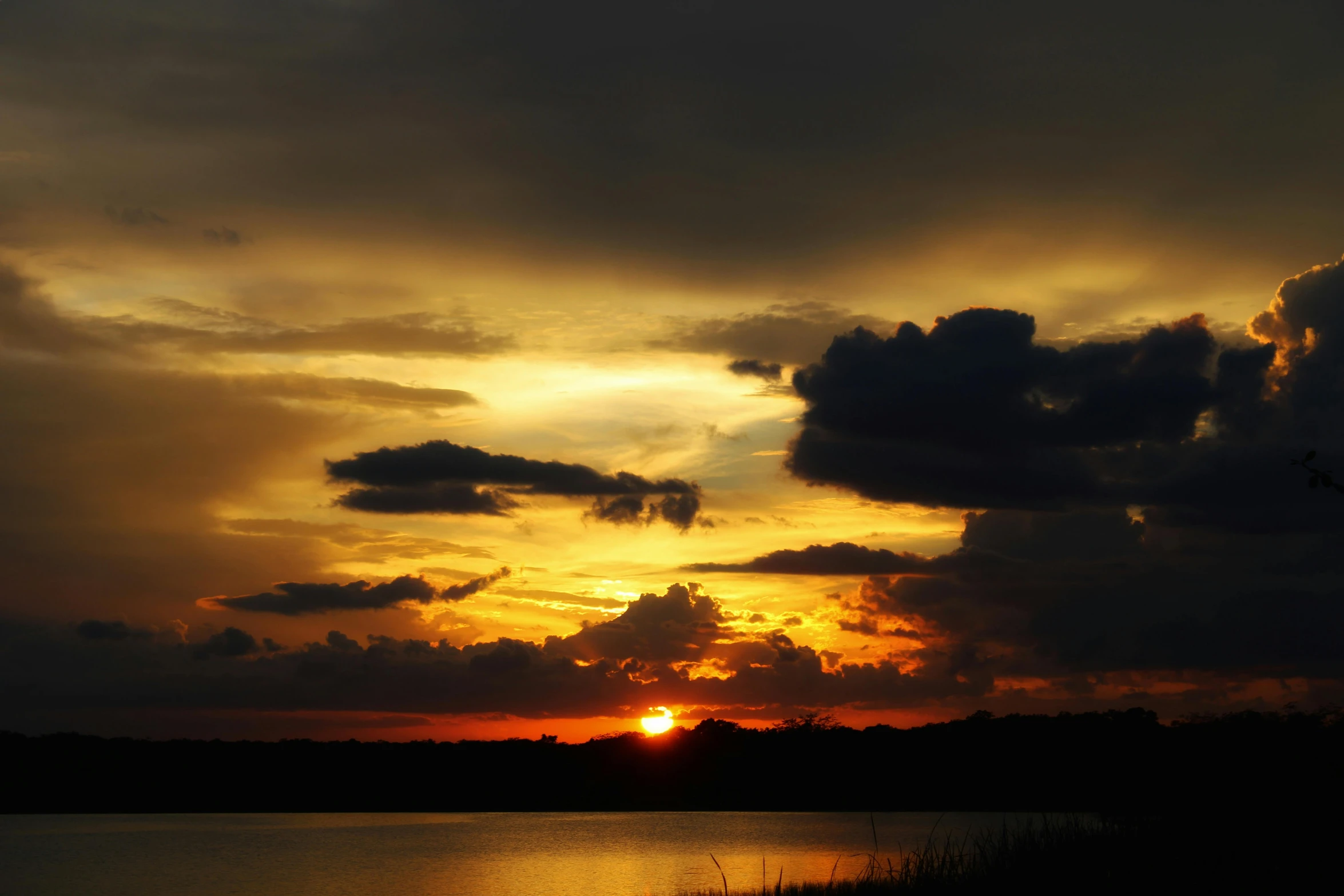 the sun is setting in front of a body of water