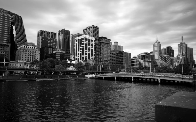 black and white pograph of boats in river next to skyline