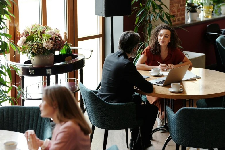 a woman in brown sitting at a table in front of another lady