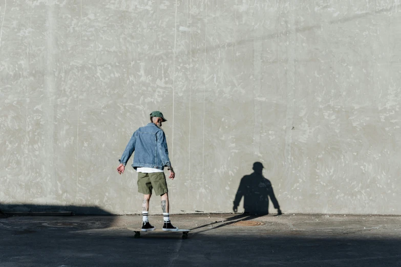 a man on his skateboard walking and casting a shadow