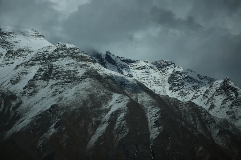 a snow covered mountain in a dark, cloudy sky