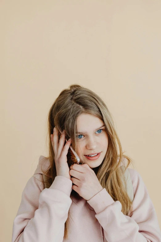 a girl wearing a sweater holding her hand in front of her face