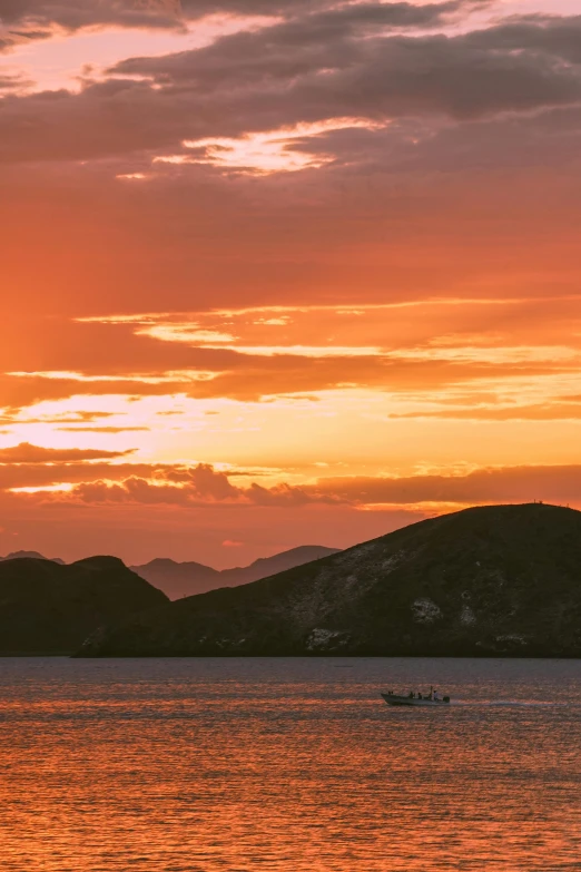 a boat floating in the water with a sunset in the background