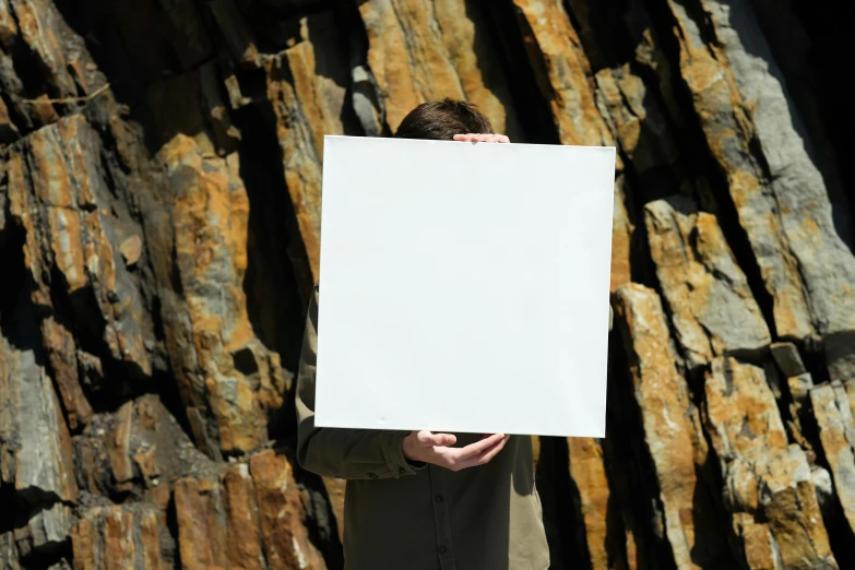 a man holds a sign in front of his face