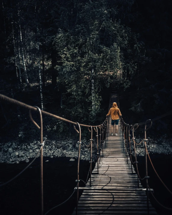 the lady is walking over a wooden bridge