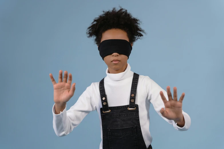 the child with the blindfolded face holds his hands out