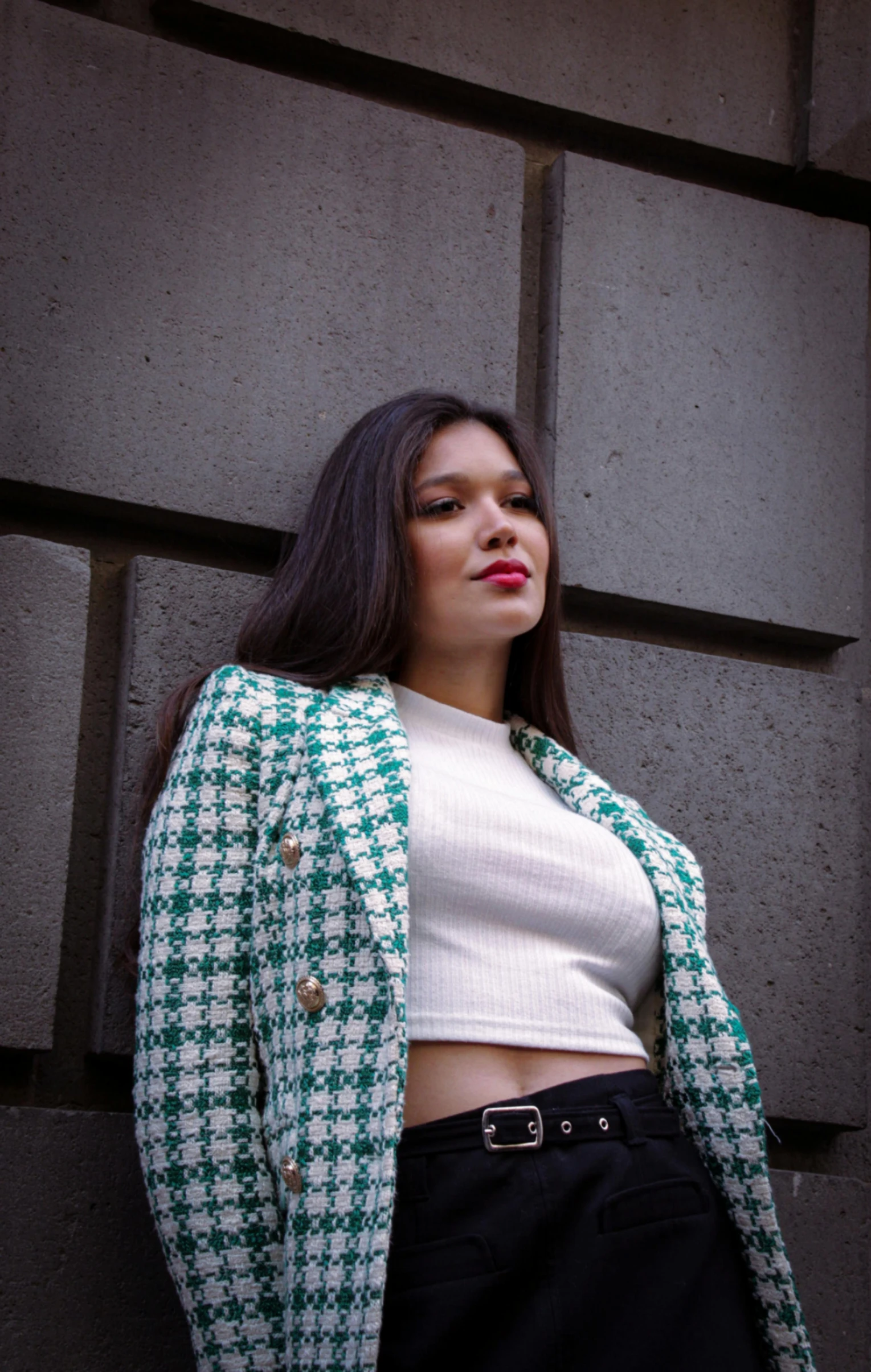 a young woman is standing near a wall