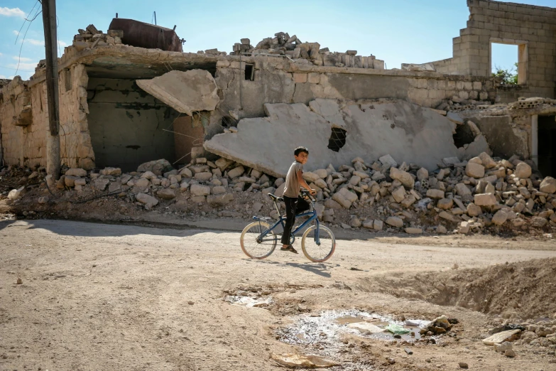 a man riding his bike in an area with ruins and other buildings