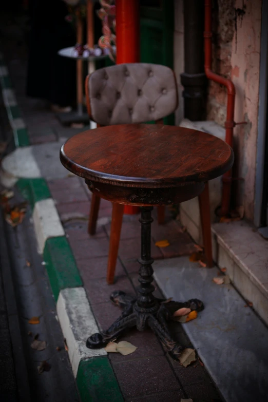 a round wooden table sitting on the side of a sidewalk