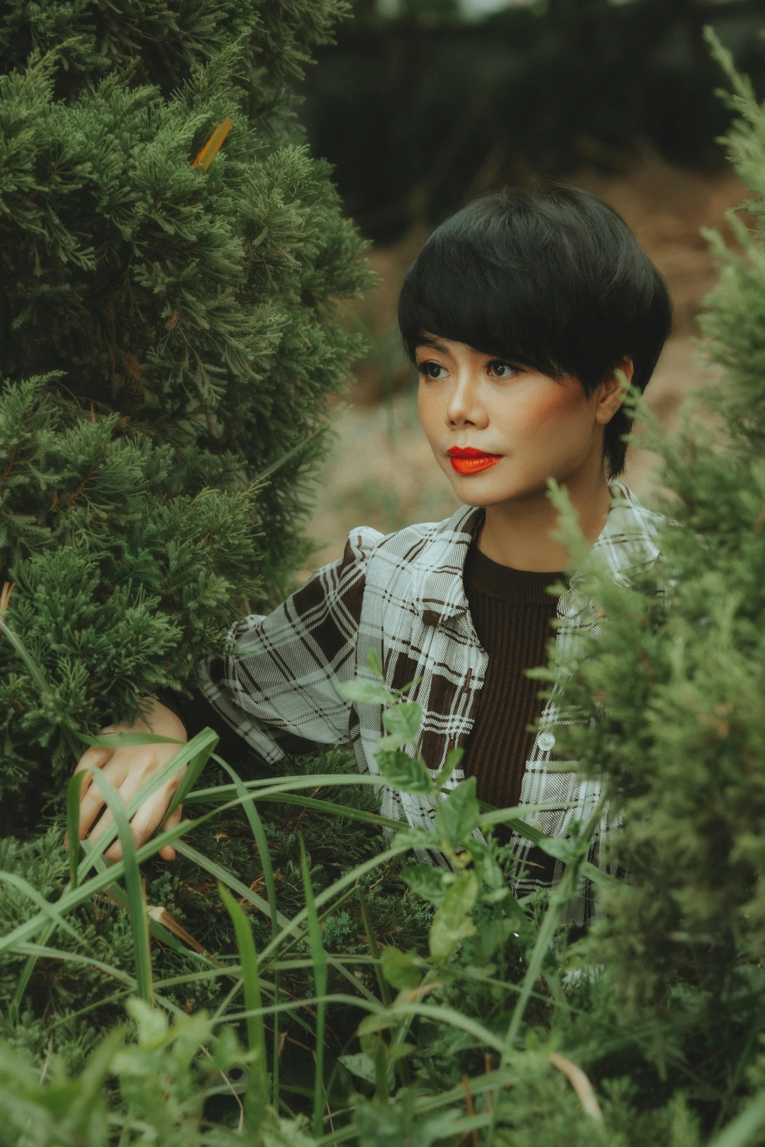 a young woman is hiding behind bushes while posing
