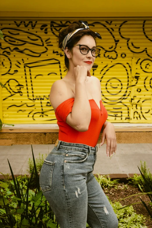 a young woman in a red top leaning on the steps next to some plants