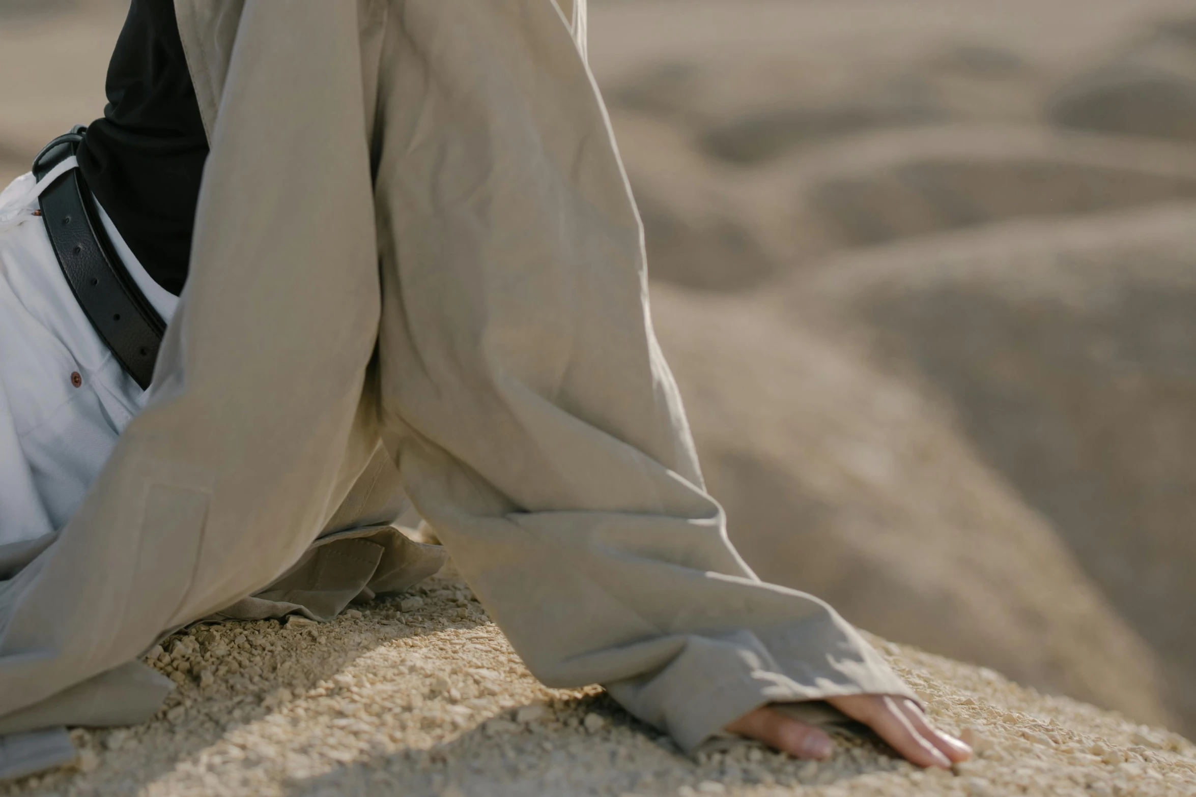 a person sitting on the sand wearing all white