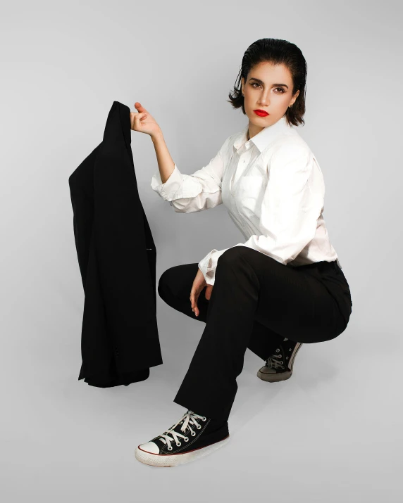 woman sitting down wearing a white shirt and black pants