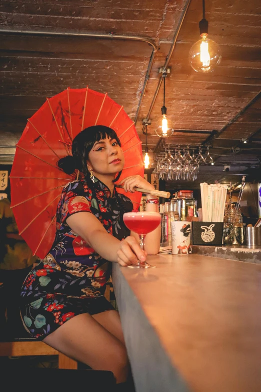 the woman is behind a bar with a red umbrella