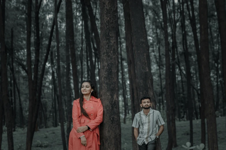 two people standing in a forest with trees
